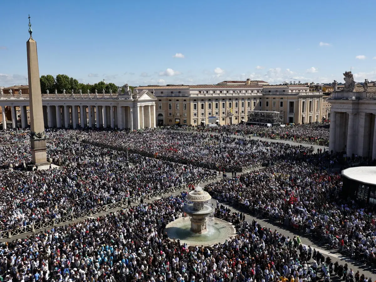 A massive crowd of people gathers together in a large public square surrounded by grand buildings.